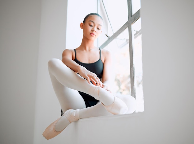 Klaarmaken voor de repetities. Shot van een vrouwelijke ballerina zittend op een vensterbank.