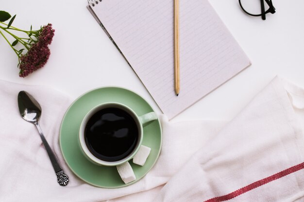 Kladblok en kopje koffie op wit.