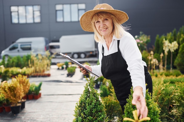 Kladblok in handen Senior vrouw is overdag in de tuin Conceptie van planten en seizoenen