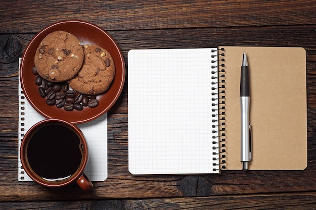 Foto kladblok, kopje koffie en koekjes op een houten tafel, bovenaanzicht. ruimte voor uw tekst