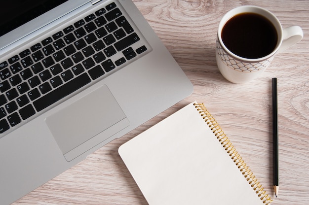 Kladblok, laptop en koffiekopje op houten tafel