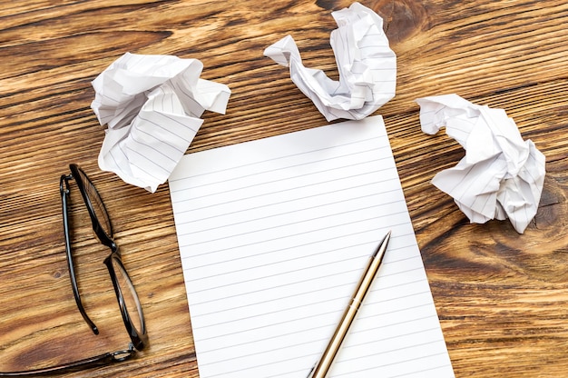 Kladblok met pen en gekreukte vellen op het bureau