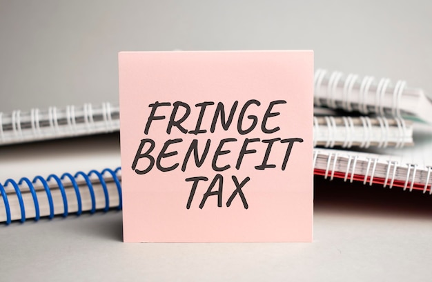 Kladblok met tekst FRINGE BENEFIT TAX, met zwarte stift op witte achtergrond