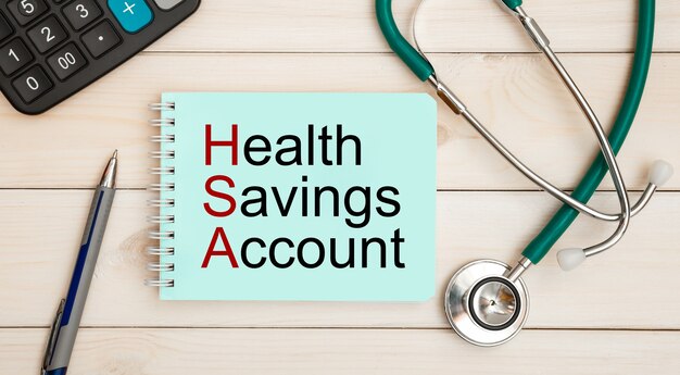 Kladblok met tekst health savings account hsa, rekenmachine en stethoscoop