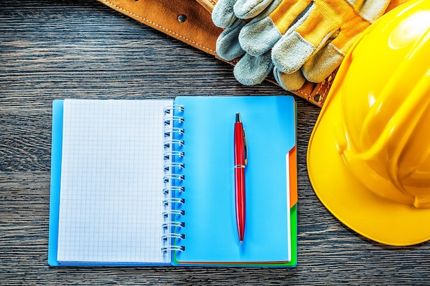 Kladblok pen gereedschapsriem beschermende handschoenen bouwhelm op houten bord