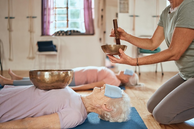 Klankschaalgenezing en senior yoga vrouw beoefent alternatieve geneeskunde audio holistische wellness of muziektherapie meditatie Yogi met klankschaal voor chakra energiebalans mindset of mindfulness