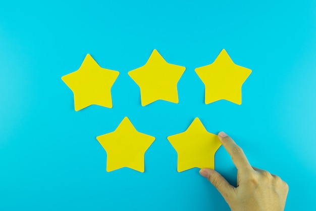 Foto klant die vijfsterren gele document nota over blauwe achtergrond houden. klantrecensies, feedback, beoordeling, ranking en serviceconcept.
