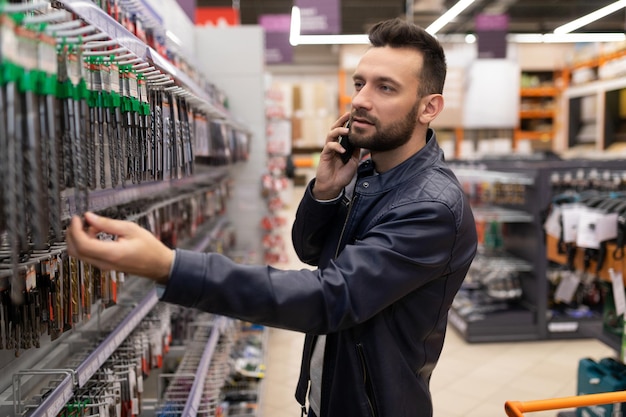 Klant man in een ijzerhandel kiest boren voor een boor en schroevendraaier