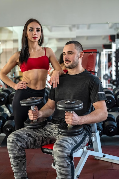 Klant met een persoonlijke trainer die aan het trainen is in de sportschool