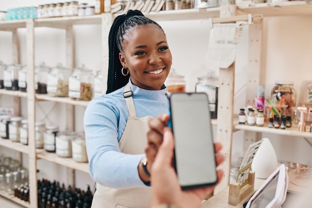 Klant zwarte vrouw en betaling met smartphone scherm financiën en machine voor transactie in een winkel Business winkel assistent en werknemer met klant mobiele telefoon en technologie met service