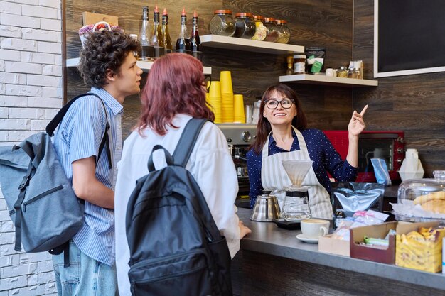 Foto klanten van een koffieshop die een bestelling plaatsen praten met een vrouwelijke barista.