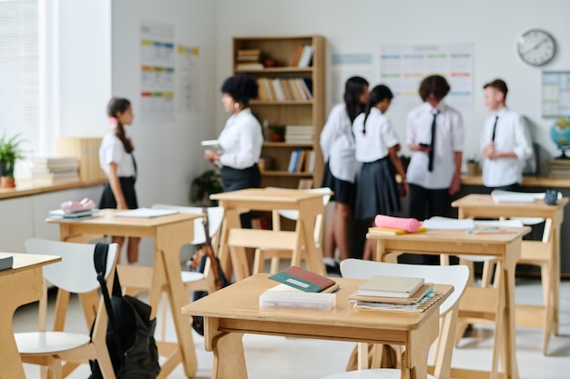 Klaslokaal met houten bureaus en studenten die op de achtergrond met elkaar praten