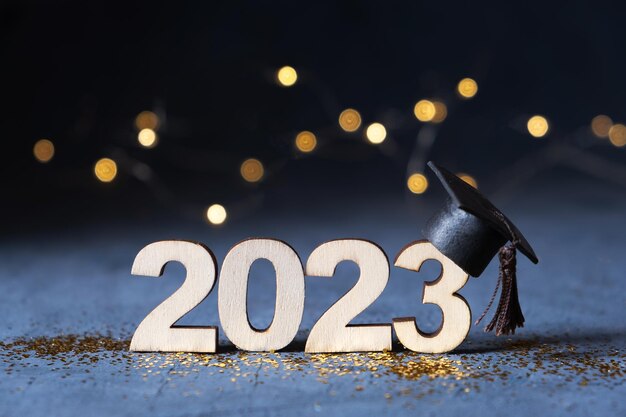 Klasse van 2023 concept Houten nummer 2023 met afgestudeerde hoed op donkere achtergrond met bokeh