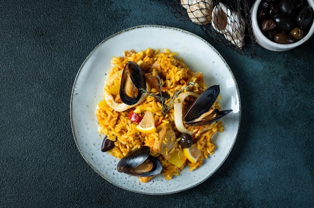 Klassiek gerecht van Spanje, zeevruchten paella in plaat op blauwe achtergrond bovenaanzicht. Spaanse paella met garnalen, klemmen, mosselen en verse citroen. Spaans eten. Troosteten. Rijst met zeevruchten.
