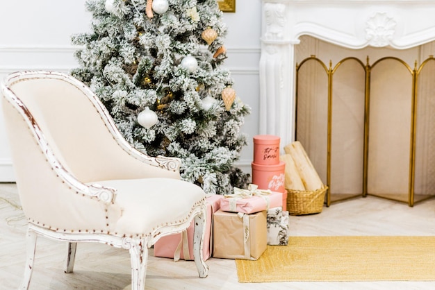 Klassiek interieur van een witte kamer met een kerstboom, slingers, lantaarns, geschenken en witte fauteuil. Foto