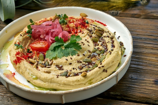 Klassiek oosters voorgerecht - kikkererwtenhummus in een witte plaat op houten. Detailopname