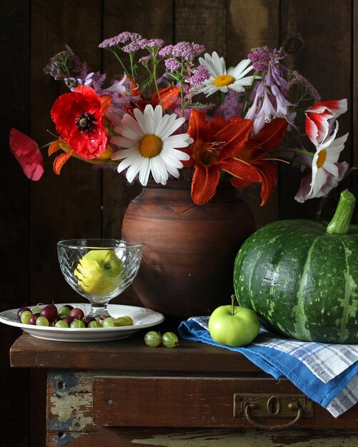 Foto klassiek stilleven met bloemen bessen en vruchten op een donkere achtergrond