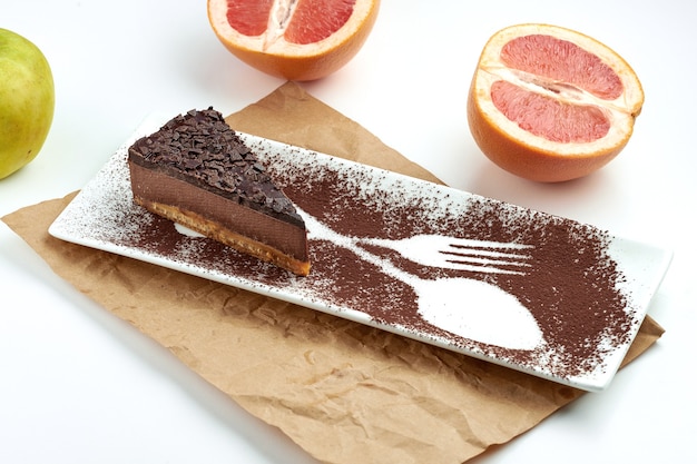 Klassiek stukje New Yorkse cheesecake met chocolade, geserveerd in een zwarte plaat op een wit oppervlak. Restaurant eten