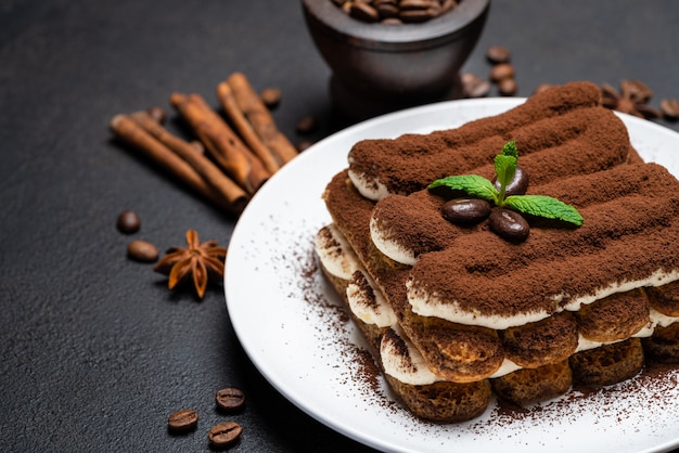 Klassiek tiramisudessert op ceramische plaat op concrete achtergrond