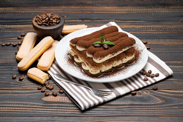 Foto klassiek tiramisudessert op ceramische plaat op houten muur of lijst