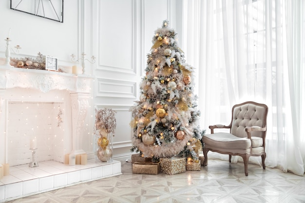 Klassiek wit kerstinterieur met versierde kerstboom. Open haard met grijze stoel, klokken aan de muur en cadeautjes onder de boom