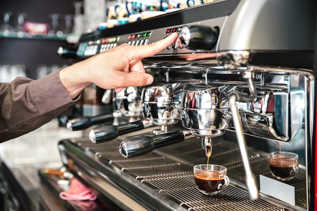 Klassieke baristahand die italiaanse espresso giet op koffiebarmachine bij modecafetaria