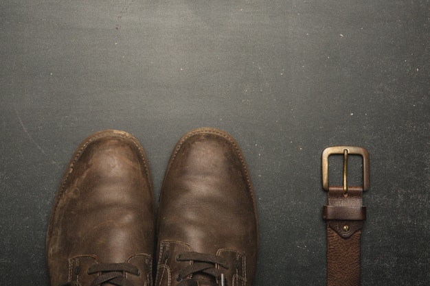 Klassieke bruine schoenen en riem op houten tafel.