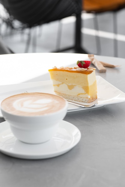 Klassieke cheesecake met verse aardbeien met kopje koffie op witte tafel. Close-up bekijken. Lekker ontbijt. Fluitje van een cent op plaat, witte kop op witte marmeren achtergrond.