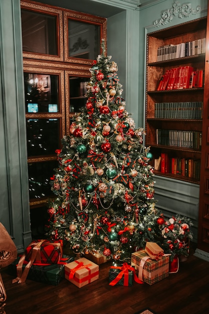 Klassieke donkere woonkamer en bibliotheek Nieuwjaar interieur met versierde kerstboom