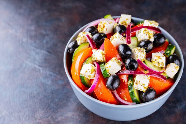 Klassieke Griekse salade met feta en olijven op een donkere achtergrond. Dieet en gezonde mediterrane salade. Ruimte kopiëren. Bovenaanzicht