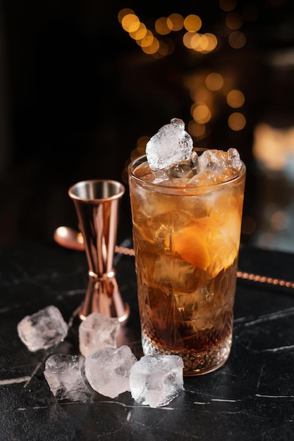 Klassieke long island ice tea cocktail met jigger en ijsblokjes