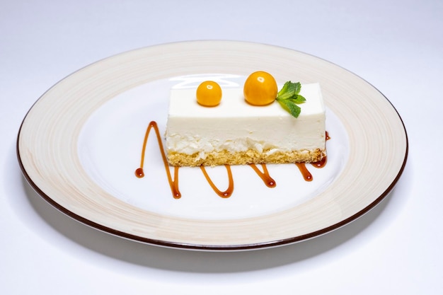 Klassieke New Yorkse cheesecake met physalis en siroop op een witte plaat en heerlijke achtergrond
