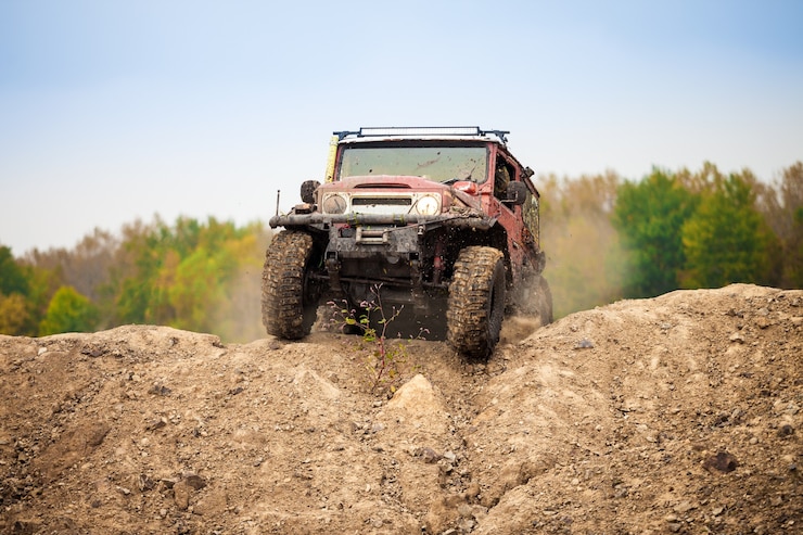 Klassieke rode off-road auto die zich op onverhard terrein beweegt