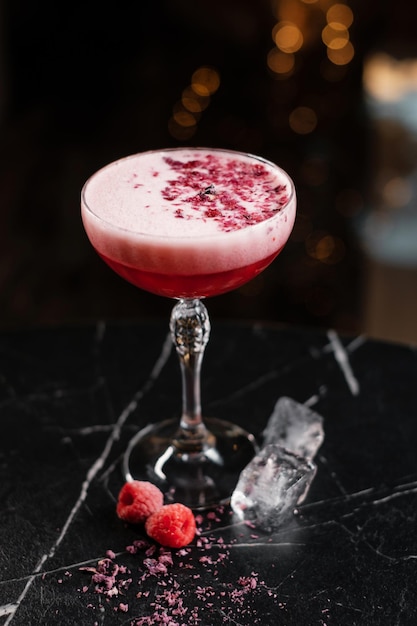 Klassieke roze cocktail gegarneerd met gedroogde bloemen en frambozen