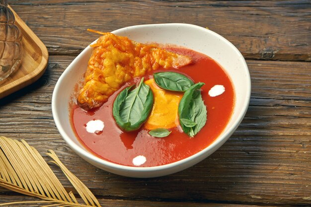 Klassieke spaanse tomatengazpachosoep met kaascroutons in een witte kom op een houten lijst