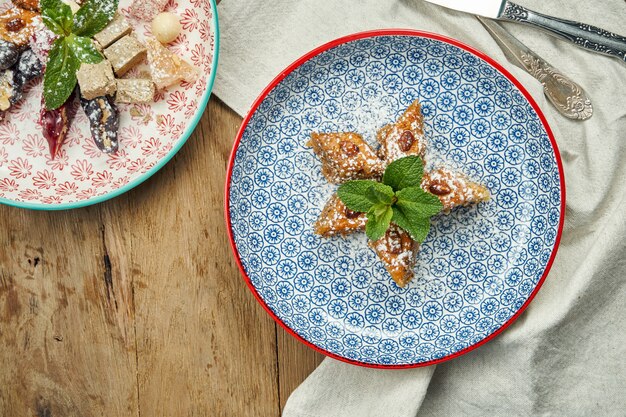 Klassieke Turkse baklava met pistachenoten en honing in een keramische plaat op een houten oppervlak. Turkse gebakjes en snoep. Detailopname