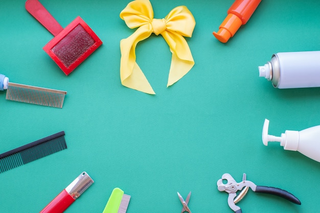 Klassieke verzorgings- en kappershulpmiddelen op een groene achtergrond: vernis, kammen, lotions, borstel, gele strik. Bovenaanzicht, cirkellay-out, lay-out, kopieerruimte