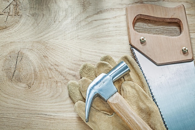 Klauwhamer lederen veiligheidshandschoenen roestvrij ijzerzaag op houten bord bouwconcept