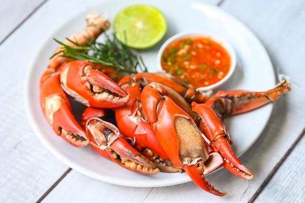 Klauwkrab koken voedsel zeevruchten plaat met chili kruiden specerijen citroen limoen salade verse krab op witte plaat zeevruchten saus gekookt of gestoomde krab rood in het restaurant