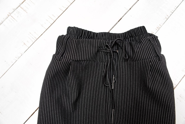 Kleding mode-concept. Detail van zwarte broek op witte houten achtergrond. Bovenaanzicht