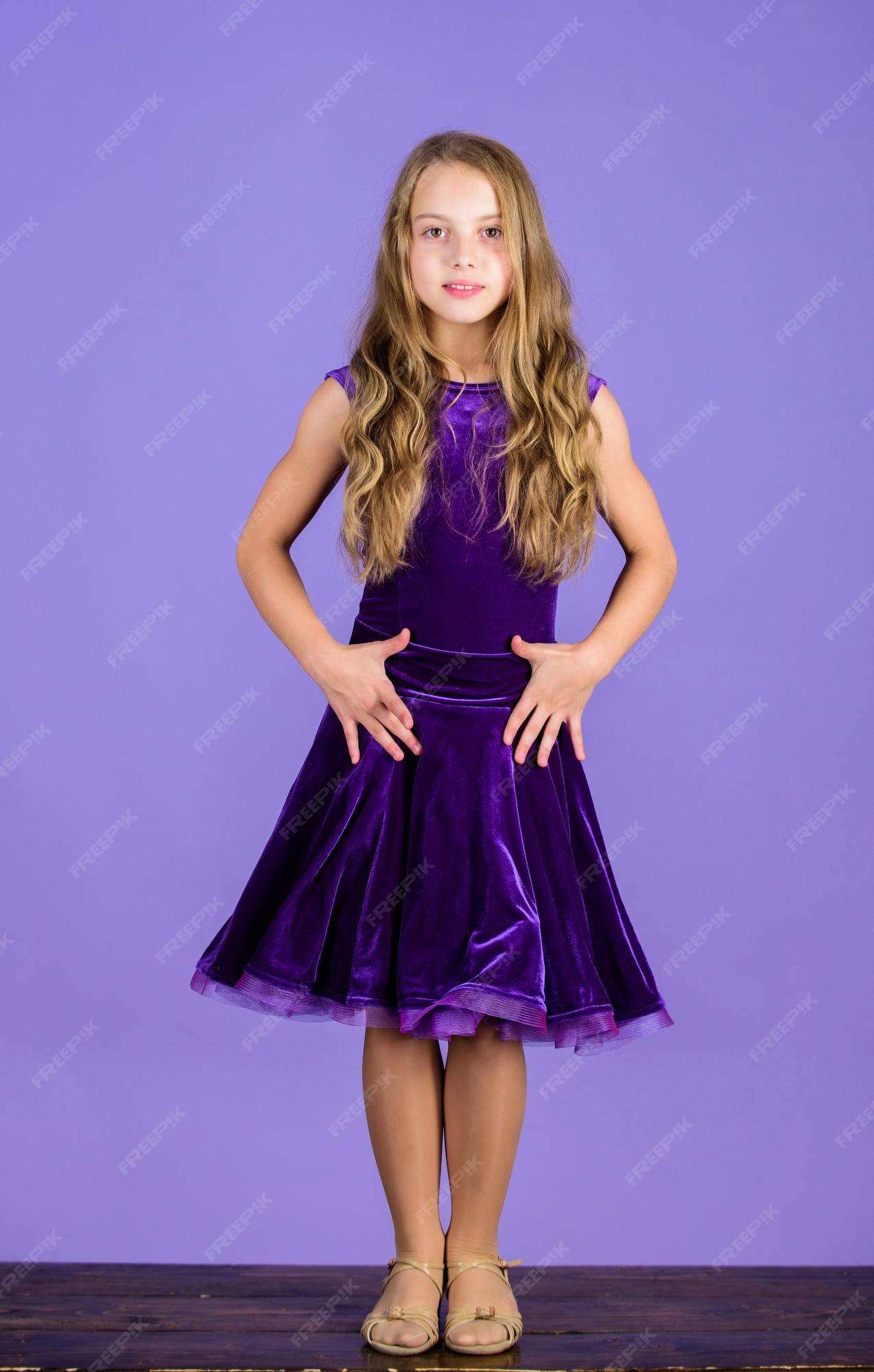 Kleding voor stijldansen. kid ziet er uit. ballroom danskleding mode concept. kid danser tevreden met concert outfit. kinder mode. meisje schattig kind draagt fluwelen violette jurk. | Premium Foto