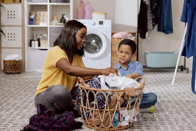 Kleding wassen in de wasmachine wasruimte badkamer vrouwen en kleine jongen brengen tijd door met praten terwijl ze huishoudelijke klusjes doen moeder legt uit aan zoon leert hem hoe hij dingen op kleur moet sorteren