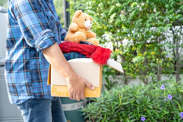 Kledingdonatiedoos met gebruikte kleding en pop thuis vasthouden om hulp aan arme mensen in de wereld te ondersteunen.