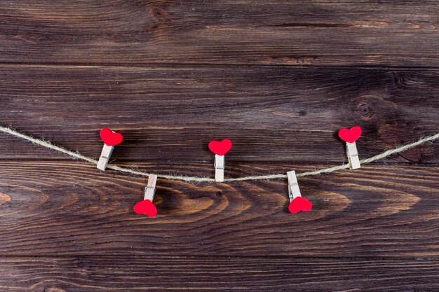 Foto kledingklemmen en rode houten harten op een touw op een donkere houten achtergrond valentijnsdagconcept
