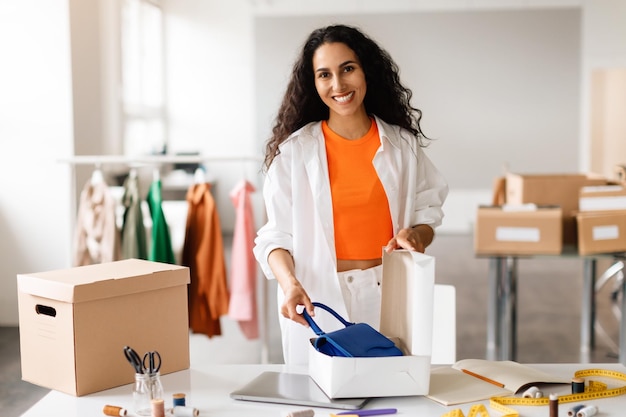 Kledingontwerper glimlacht terwijl hij handtas in een modewinkel inpakt