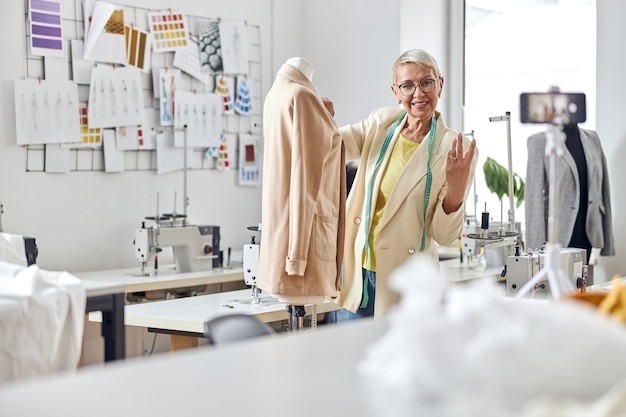 Kledingontwerper voor volwassen dames maakt video voor blog die werkt met een elegant jasje in de studio