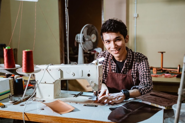 Kleermaker die lacht tijdens het gebruik van een naaimachine op het naaistation