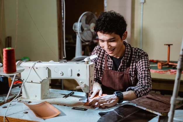 Kleermaker met behulp van een lederen naaimachine in de naaiatelier