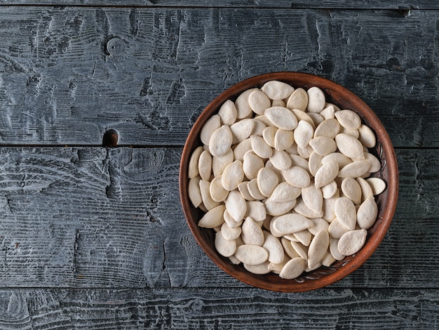 Kleikom met pompoenpitten op een zwarte houten tafel