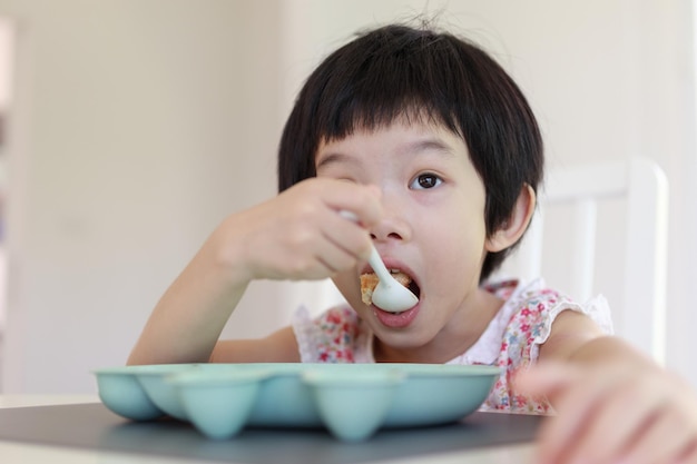 Klein aziatisch meisje aan het ontbijt